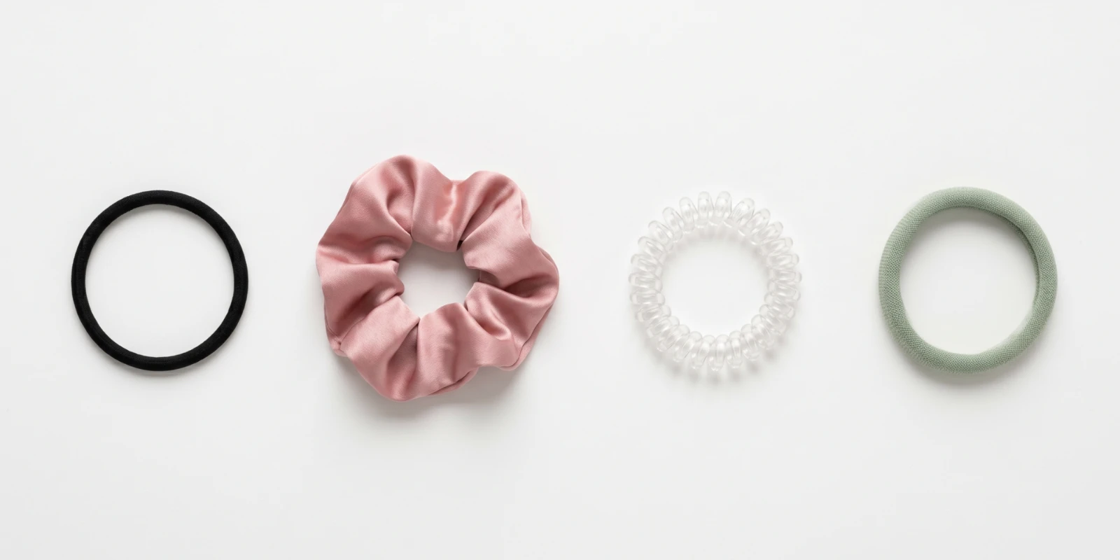 Assortment of hair ties including elastic bands, scrunchies and spiral coils displayed on a flat white surface