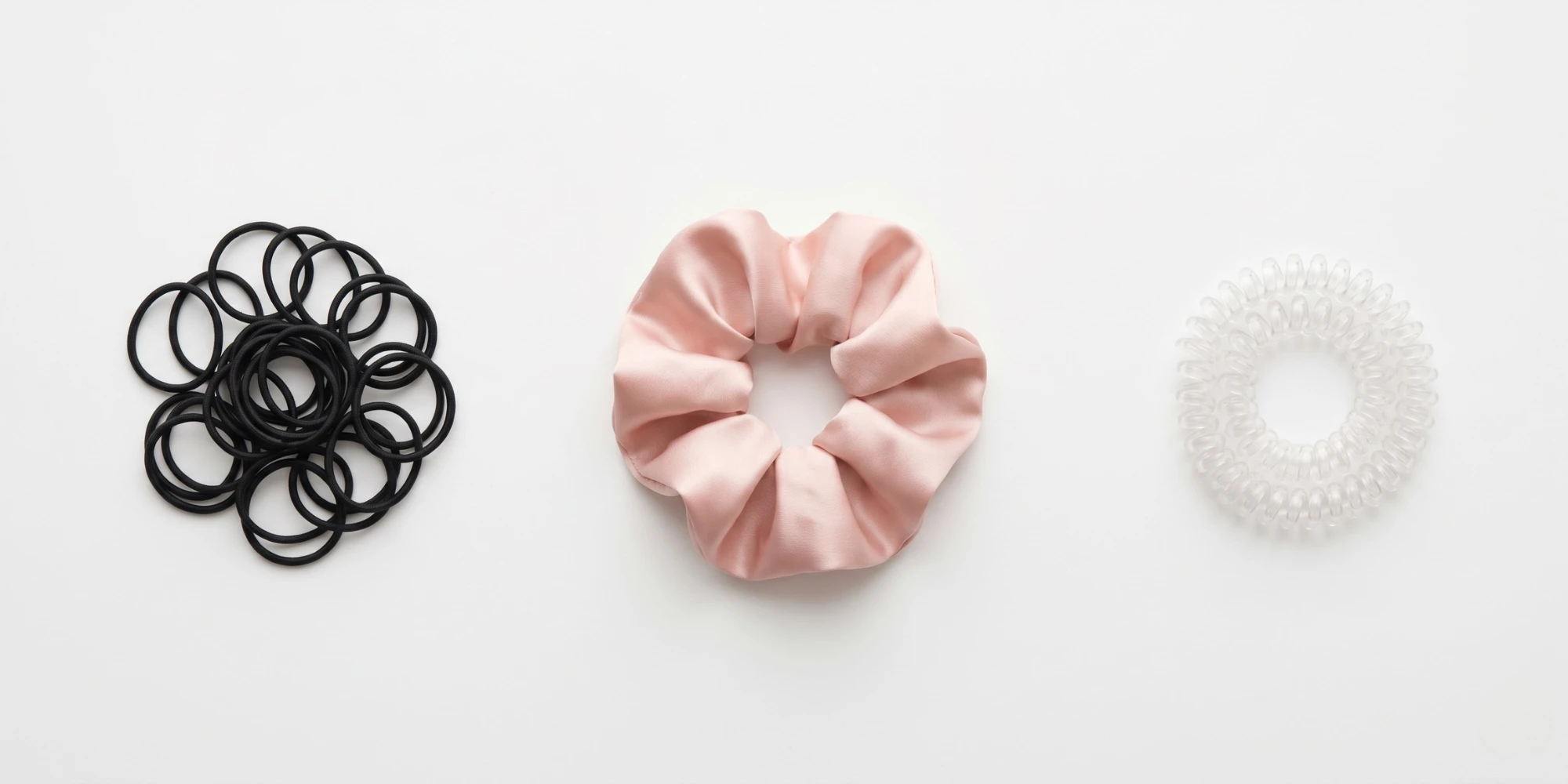 Spiral coil hair tie and satin scrunchie displayed as lower-damage alternatives to rubber elastic band for different use cases