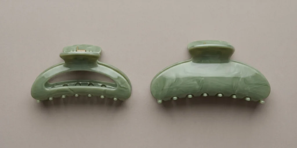Large oversized acetate claw clip shown next to standard medium clip illustrating size requirement for curly high-volume hair