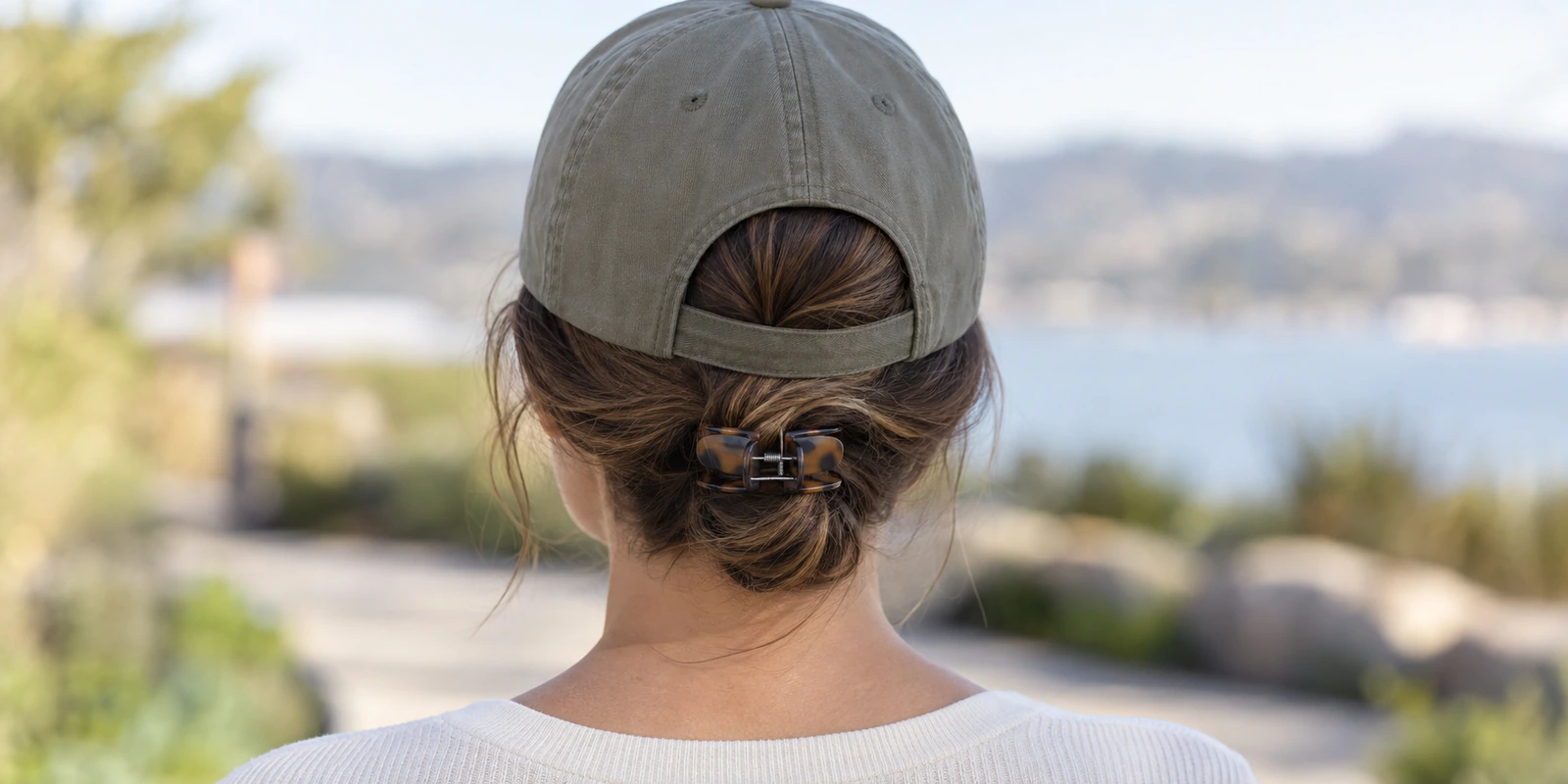 Low-profile claw clip positioned at the nape of the neck under a baseball cap