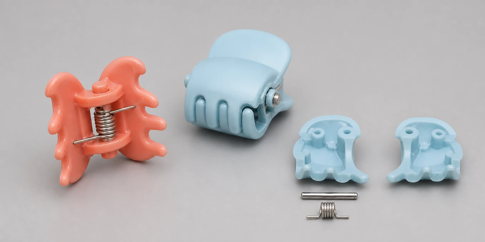 Rounded plastic children's claw clips with stainless-steel pivot pins and torsion springs shown assembled and disassembled