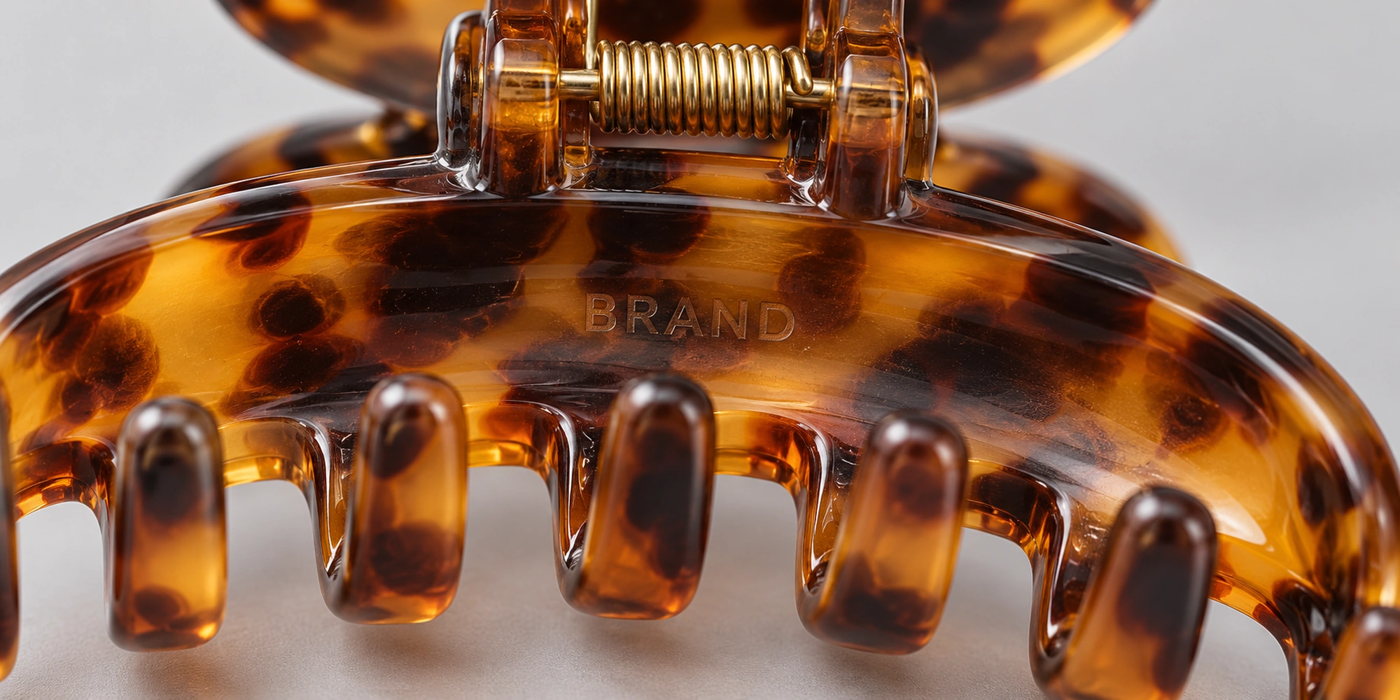 Laser engraved logo on the inner jaw of a tortoiseshell acetate claw clip, close-up